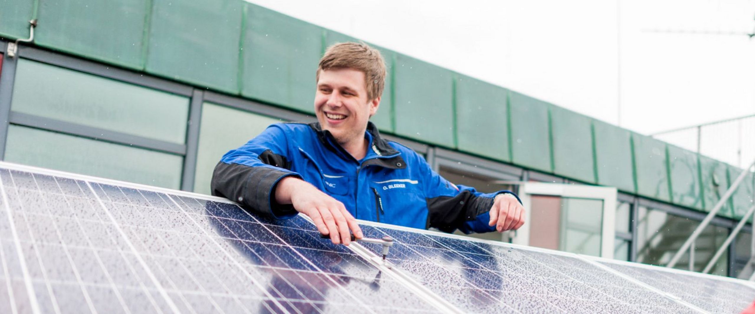 Ein Studierender betrachtet eine Photovoltaikanlage auf einem Gebäudedach.