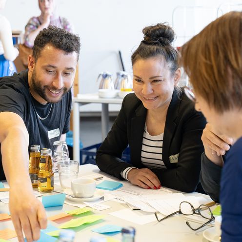 PM Diversity Café Mann und zwei frauen sitzen am Tisch und interagieren miteinander