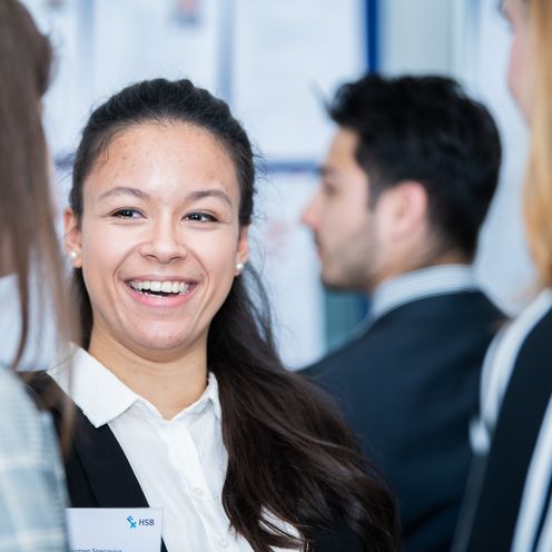 20260109_PM FIT@HSB Mentorinnen gesucht Frau steht zwischen Leuten und lacht in die Kamera