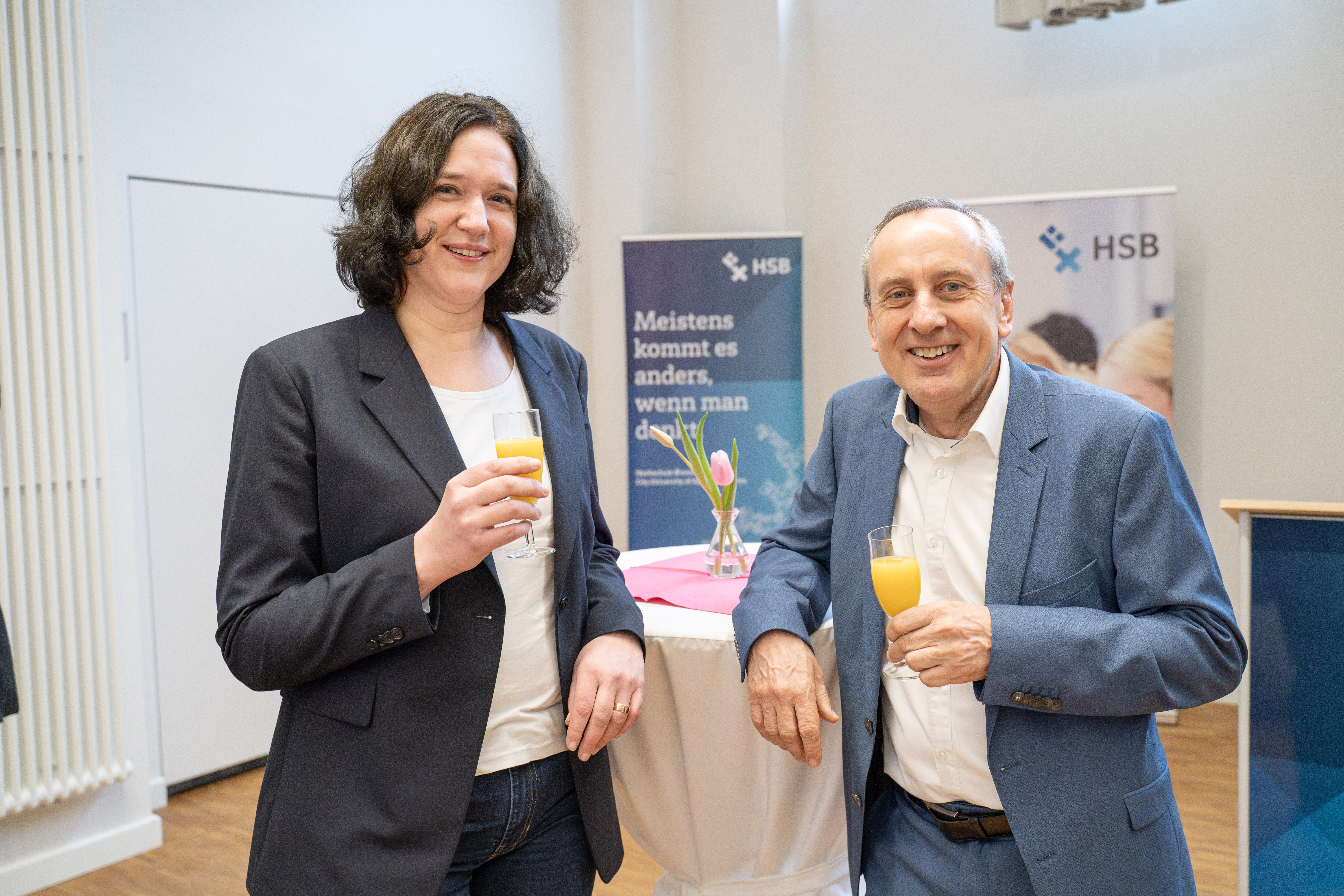 Frau und Mann halten ein Sektglas mit Orangensaft und l&auml;cheln in die Kamera 