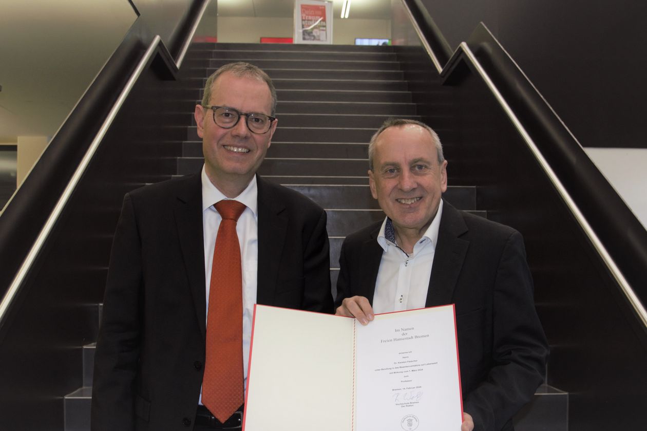 Zwei Männer halten eine Urkunde und lächeln in die Kamera