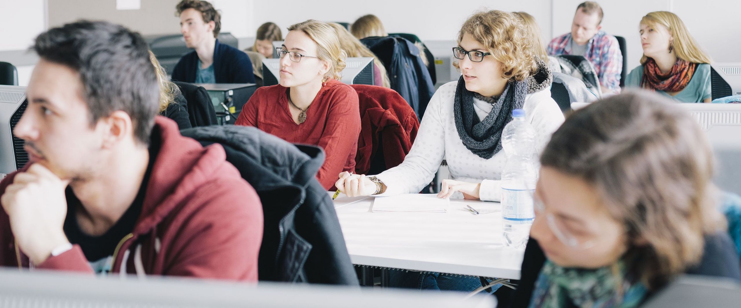 Junge Menschen sitzen in Seminarsaal und arbeiten