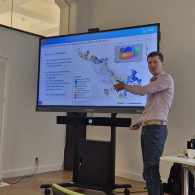 Timmy Schwarz präsentiert Forschungsergebnisse vor einem großen Monitor 