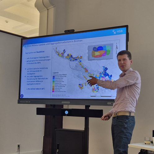 Timmy Schwarz pr&auml;sentiert Forschungsergebnisse vor einem gro&szlig;en Monitor 