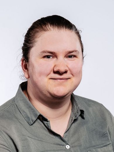 Auf dem Bild ist Julia Albers zusehen. Sie hat ihre Haare streng nach hinten gebunden und trägt eine olivfarbene Bluse