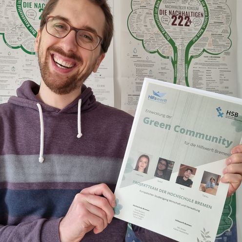Fabian Oestreicher von der Hilfswerft in Bremen h&auml;lt die Ausarbeitung der Studierendengruppe in die Kamera und freut sich &uuml;ber das Ergebnis.