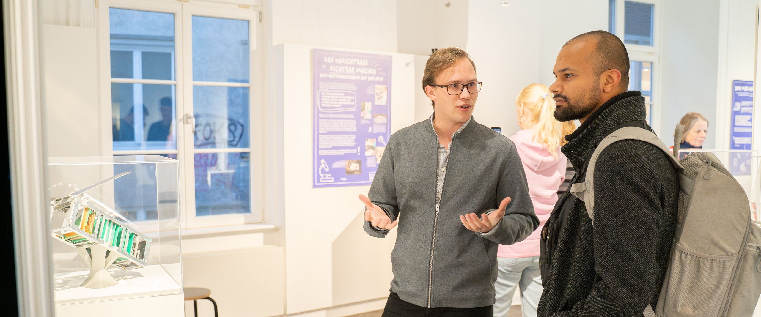 Eröffnung der Jahresausstellung im Haus der Wissenschaft. Auf dem Bild sind zwei Männer zu sehen, die vor einer Glasvitrine mit einem Modell stehen und sich unterhalten.