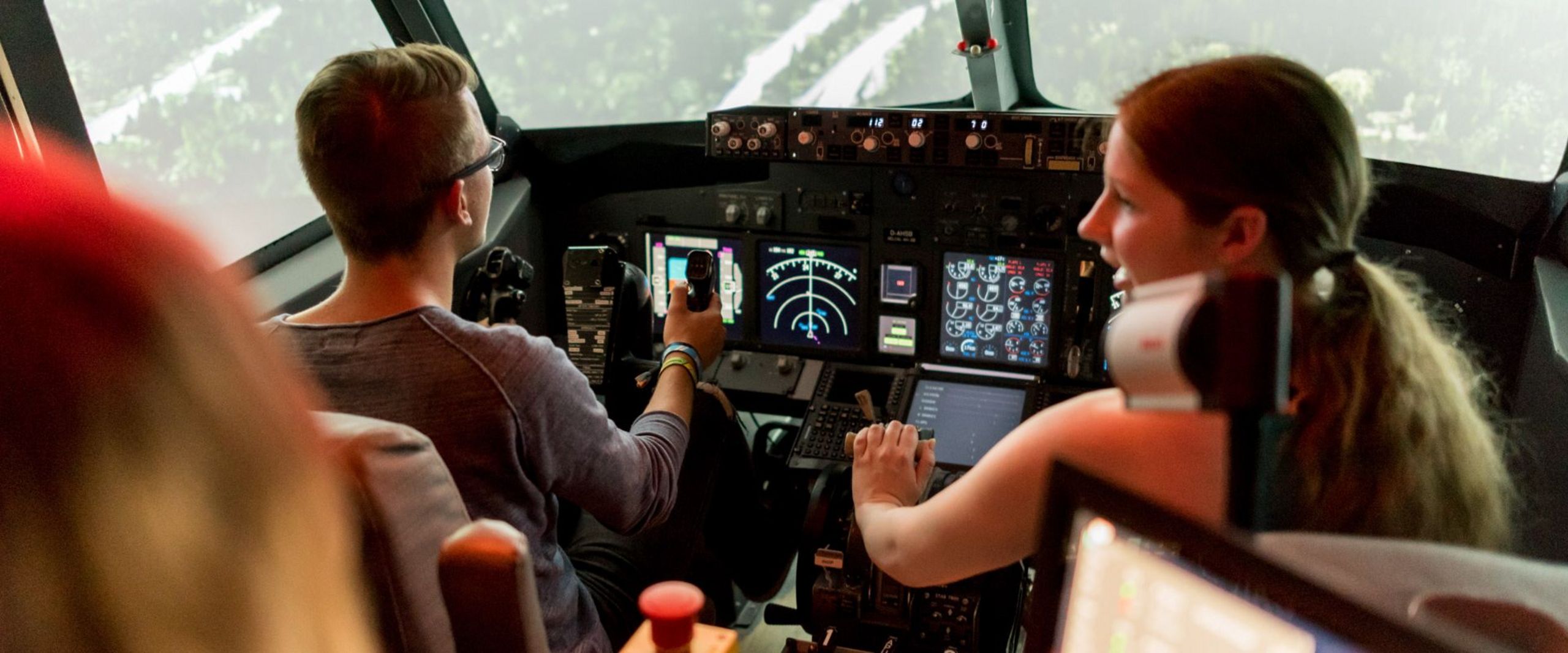 Studierende sitzen im Cockpit eines realistischen Flugsimulators.