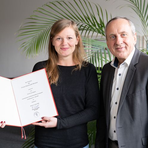 Mann und Frau mit einer Urkunde lachen in die kamera