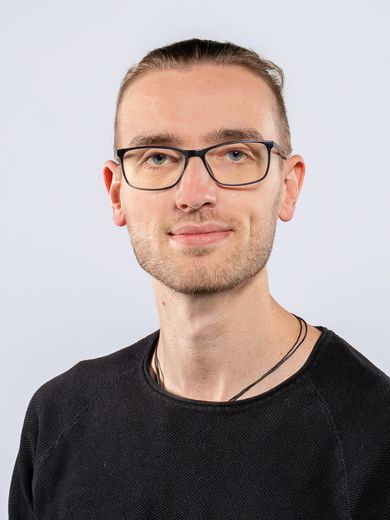 Auf dem Foto ist Andreas Brauneck zusehen. Er hat seine blonden Haare zu einem Zopf zusammengebunden. Er tr&auml;gt eine Brille und ein schwarzes Oberteil. 