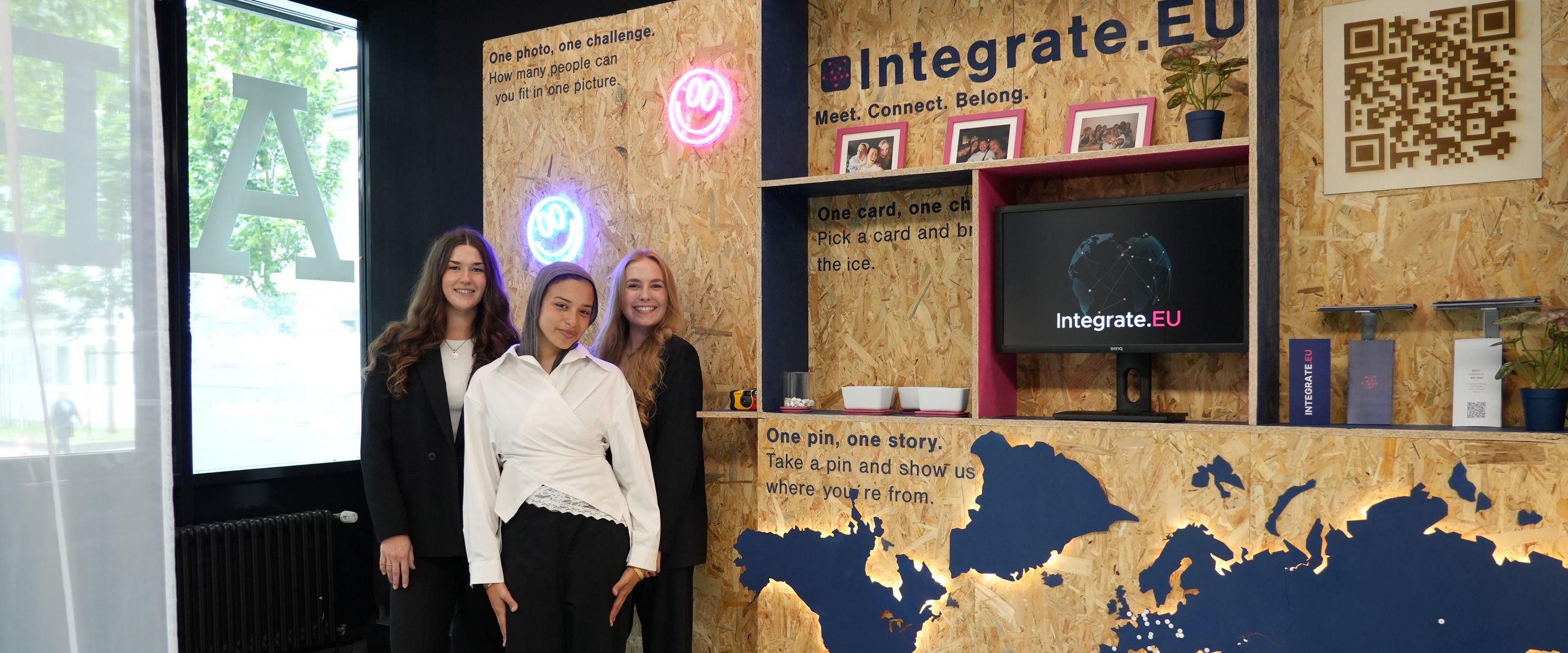 STARS EU Projekt Integrate.eu Three young women are standing in front of a display featuring a map and shelving units