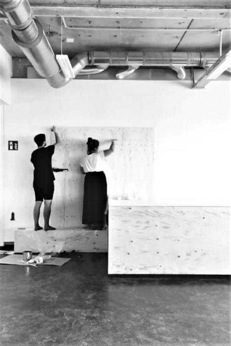 Zwei Studierende bauen eine Wand in einem Raum auf.