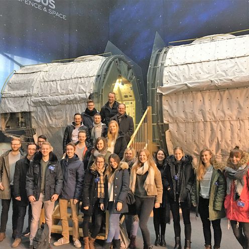 Eine Gruppe Studierender steht vor Bauteilen einer Rakete.