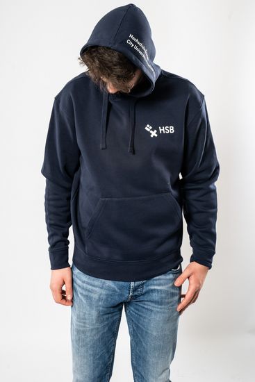 Das Model trägt einen dunkelblauen Pullover für Herren mit HSB-Logo darauf und wird dabei von vorne gezeigt.