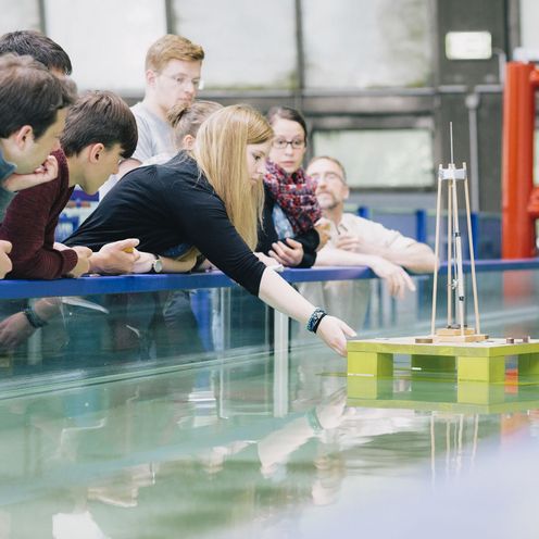 Studierende testen eine schwimmende Konstruktion in einem Wasserbecken.