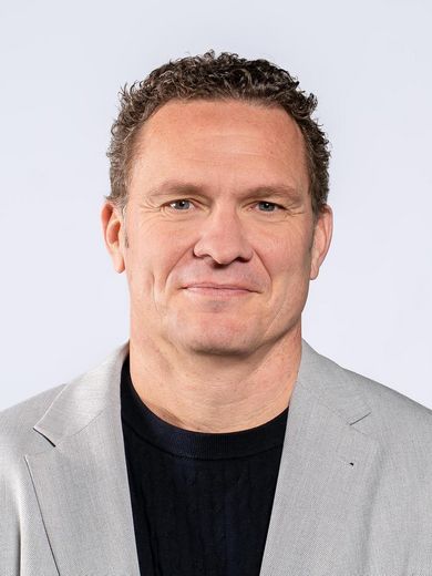 Auf dem Foto ist Jan-Hendrik Tillmann zusehen. Er hat kurzes blondes Haar und tr&auml;gt ein schwarzes T-Shirt unter einem hellgrauen Sakko.