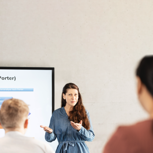 Eine vortragende Frau blickt ins Publikum 