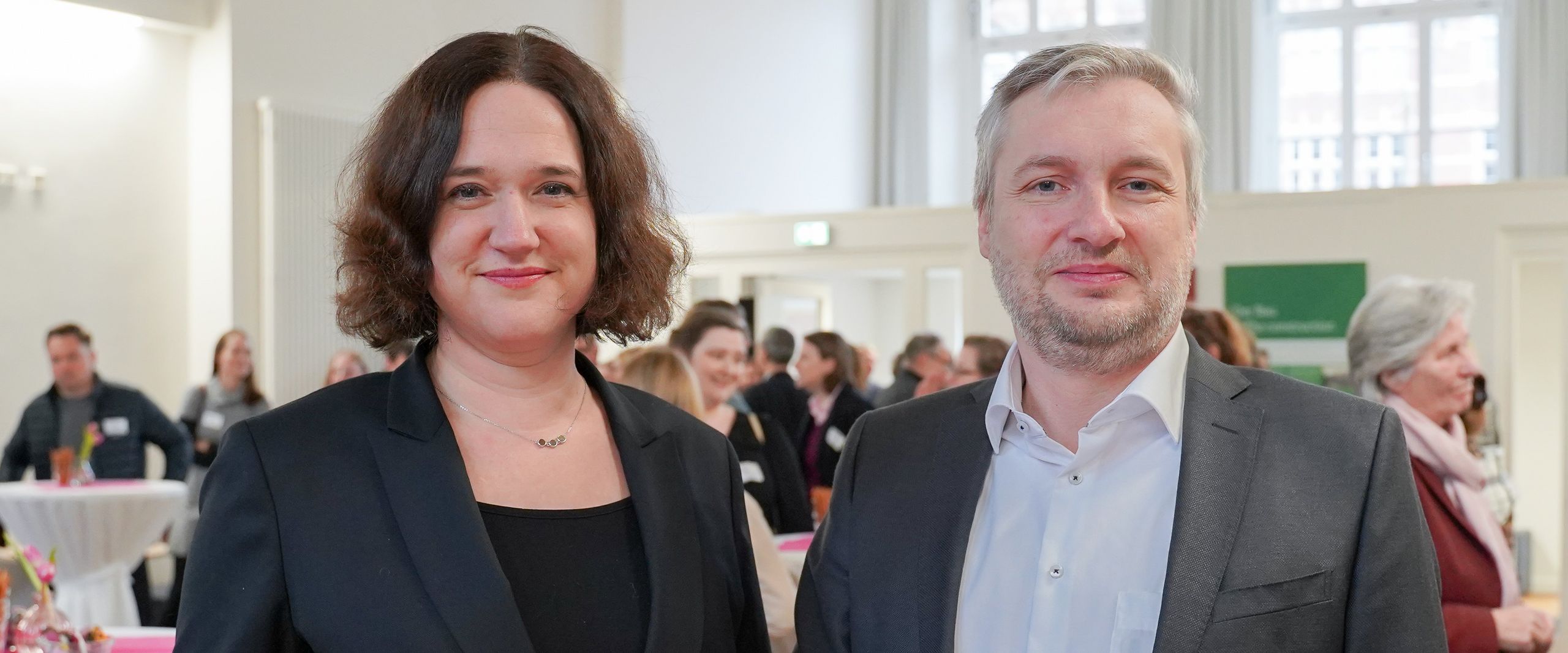 Photo of woman and man at a bar table. Both are smiling into the camera.