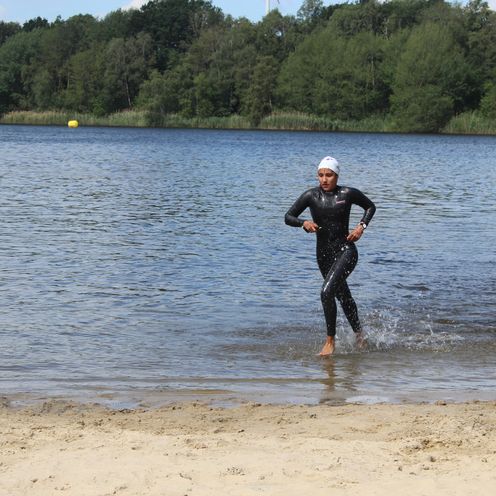 Eine L&auml;uferin rennt durch Wasser.