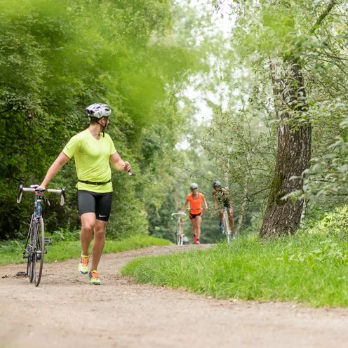 L&auml;ufer:innen sprinten die Strecke entlang und schieben gleichzeitig ein Fahrrad.