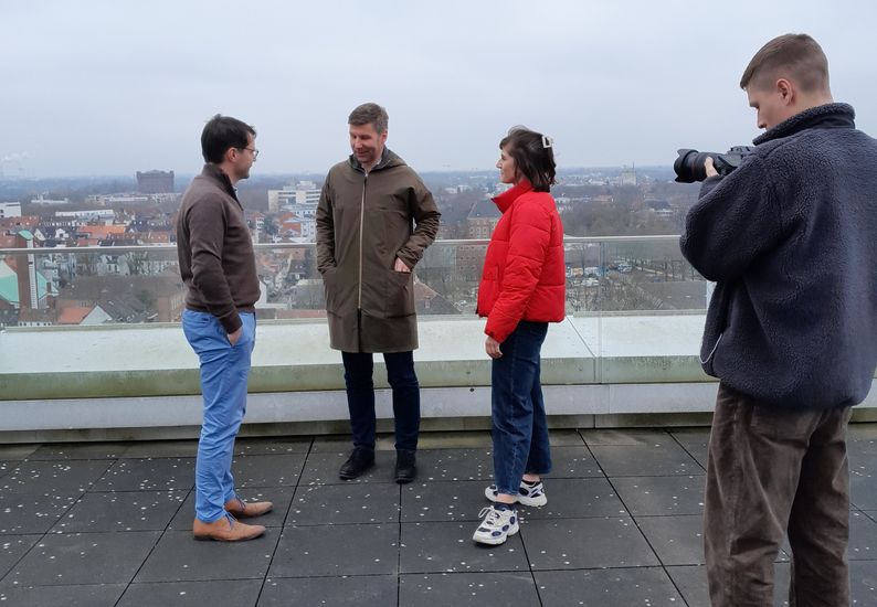 Männe rund frauen stehen auf der Dachterrasse und unterhalten sich. 