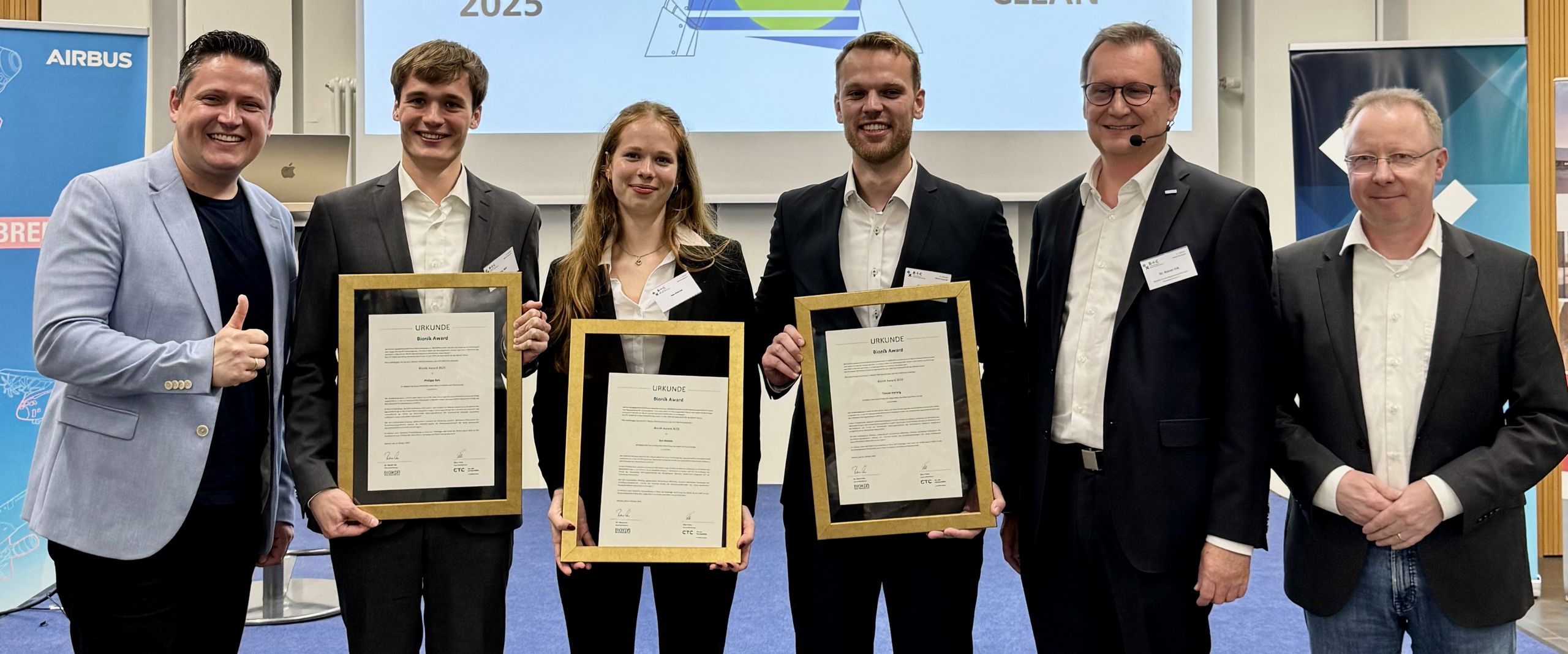 Bionik-Award 2025 Gruppenbild mit Männern und Frau. Drei Personen halten eine gerahmte Urkunde.