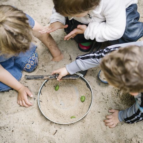 Drei Kinder in einem Sandkasten, Ansicht von oben