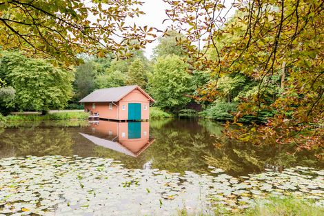 Ein Bootshaus an einem See umgeben von Bäumen im Bremer Bürgerpark.