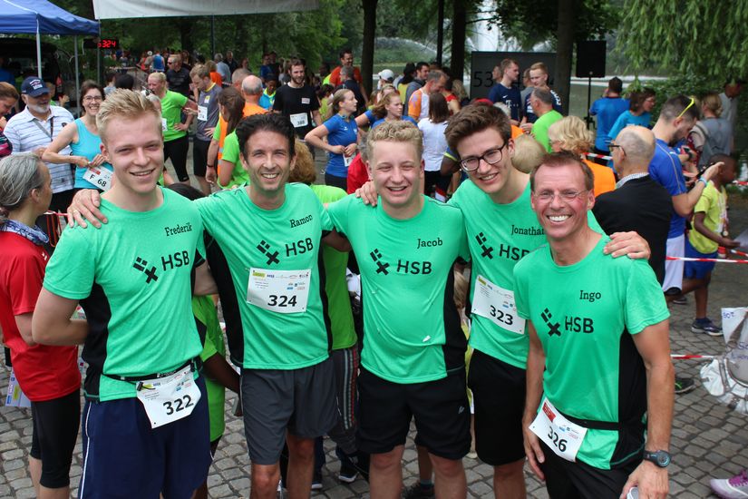 Gruppenbild von fünf Läufern. Im Hintergrund stehen mehrere Menschen.