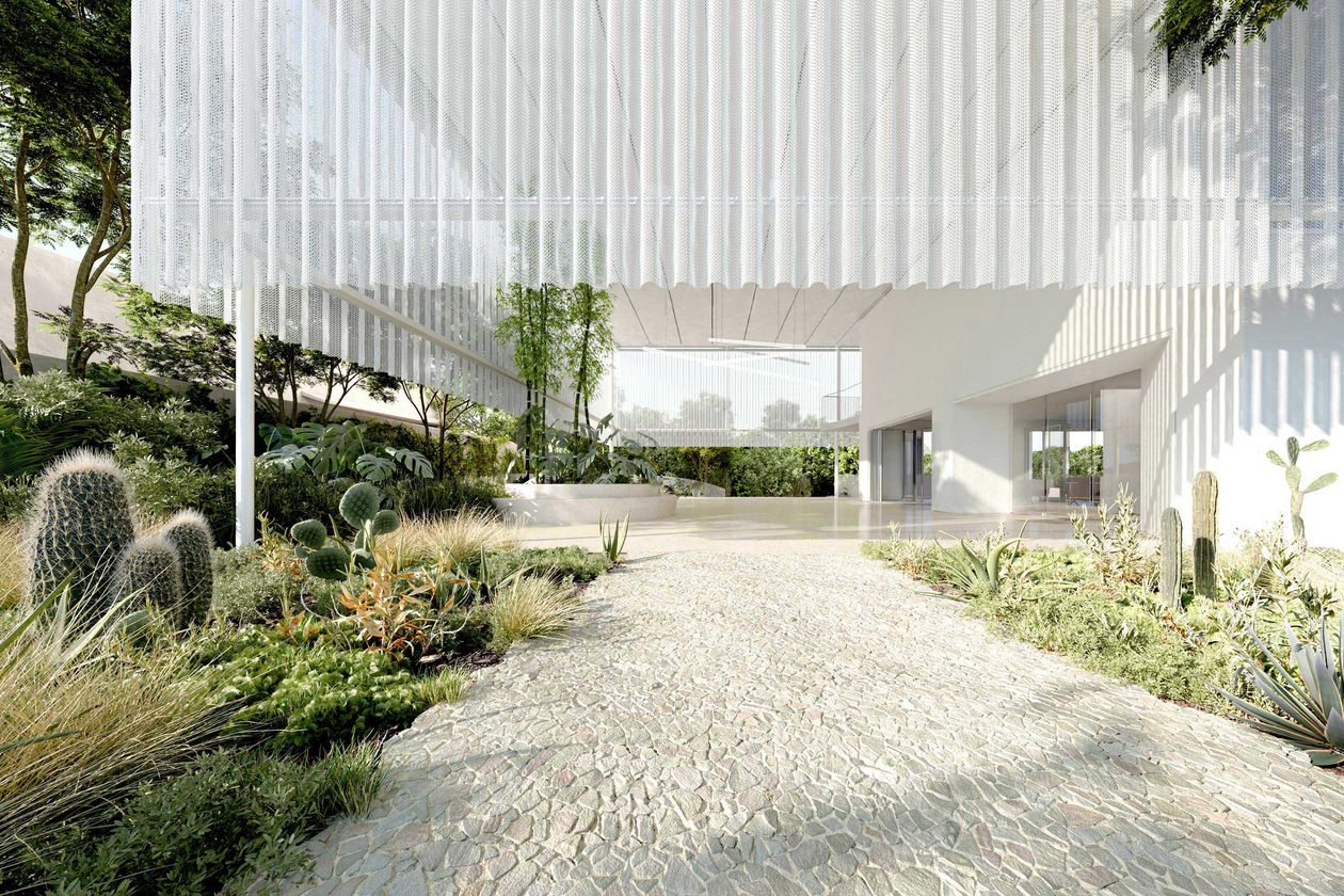 Das Bild zeigt den Ausschnitt eines modernen, weißen Gebäudes mit Weg und Grünbepflanzung am Rande