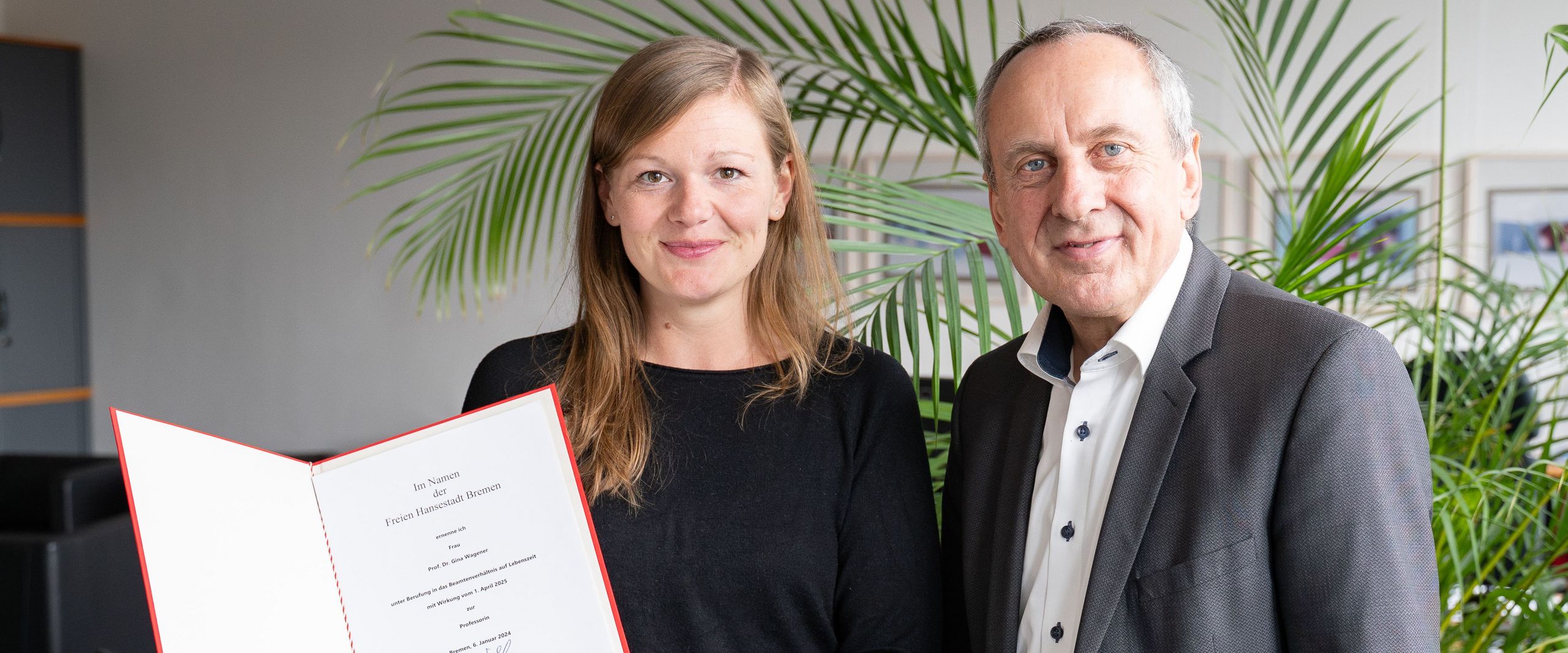 Mann und Frau mit einer Urkunde lachen in die kamera
