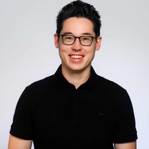 Portrait eines jungen Mannes mit kurzen schwarzen Haaren und Brille.