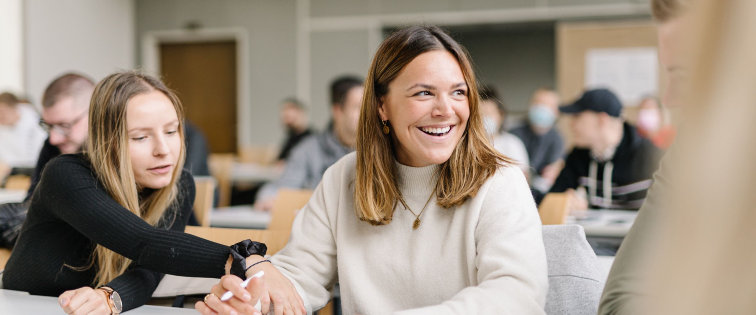 Studierende MiH Studentinnen vom Studiengang Management im Handel unterhalten sich bei einer Gruppenarbeit in einer Veranstaltung.