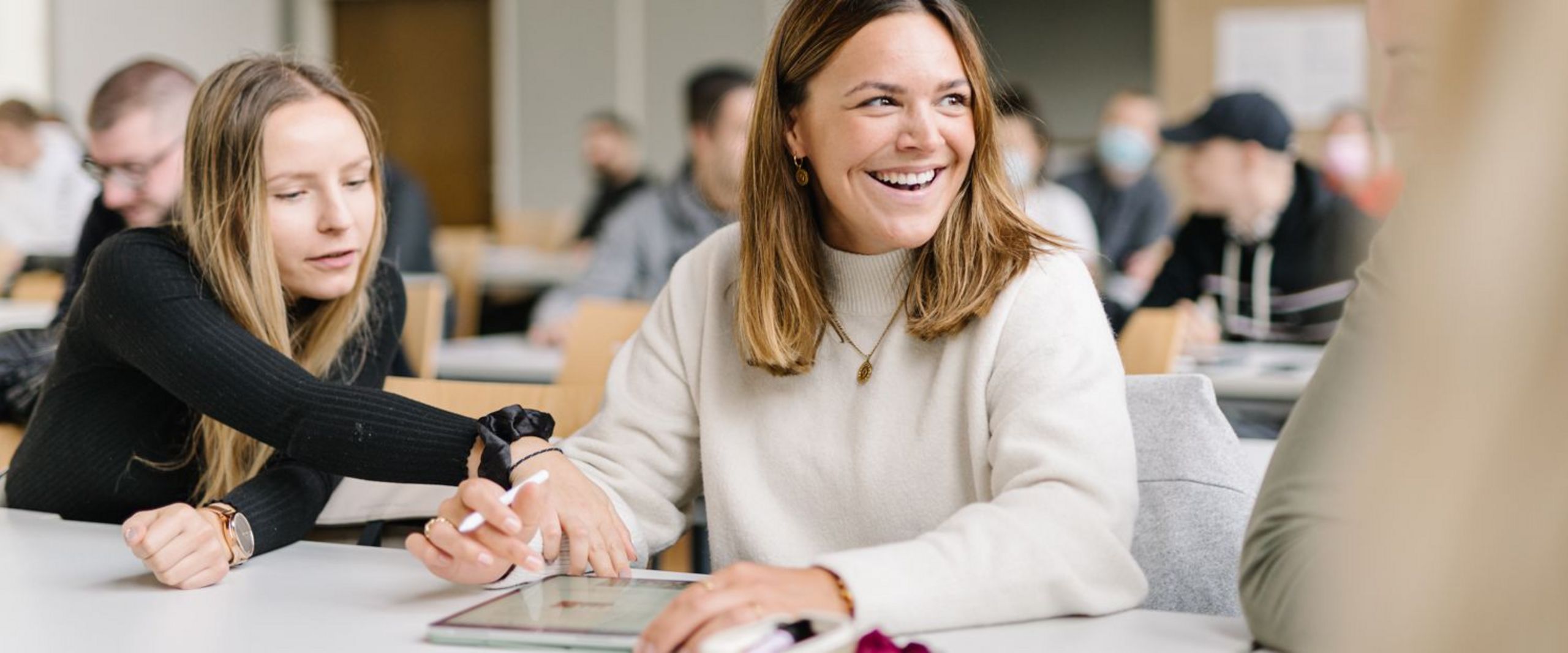 Studentinnen vom Studiengang Management im Handel unterhalten sich bei einer Gruppenarbeit in einer Veranstaltung.