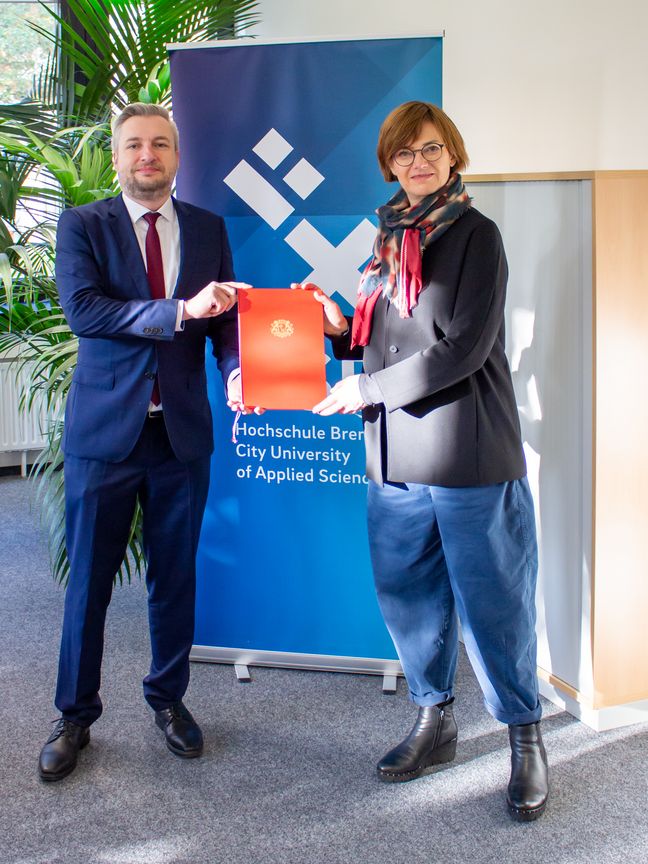 Kanzler Daniel Engelbrecht &uuml;berreicht Prof. Dr. Svenja Tams eine Urkunde ihrer Berufung als Professorin an die HSB.