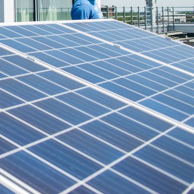 Studierende stehen auf dem Dach eines Gebäudes und betrachten eine Solaranlage.