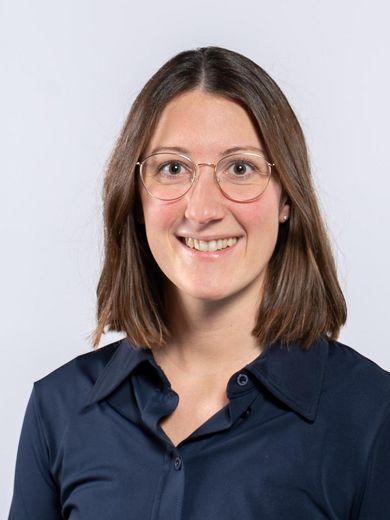 Auf dem Foto ist Sarai Wosnik zusehen. Sie hat schulterlanges, braunes Haar. Sie tr&auml;gt eine Brille und eine dunkelblaue Bluse.