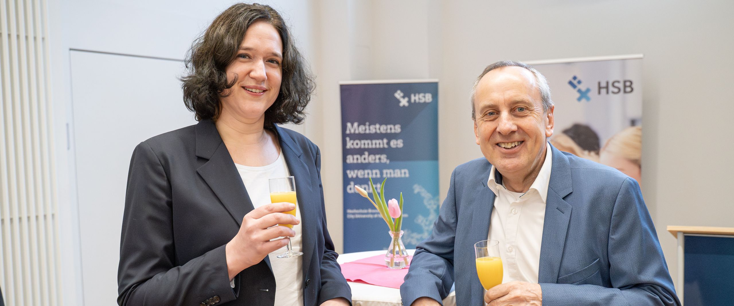 Frau und Mann halten ein Sektglas mit Orangensaft und l&auml;cheln in die Kamera 