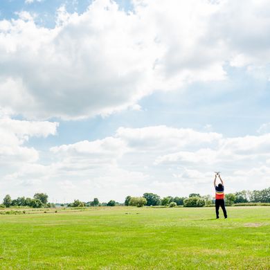 Eine Wiese an einem sonnigen Tag. Hinten rechts steht eine Person.