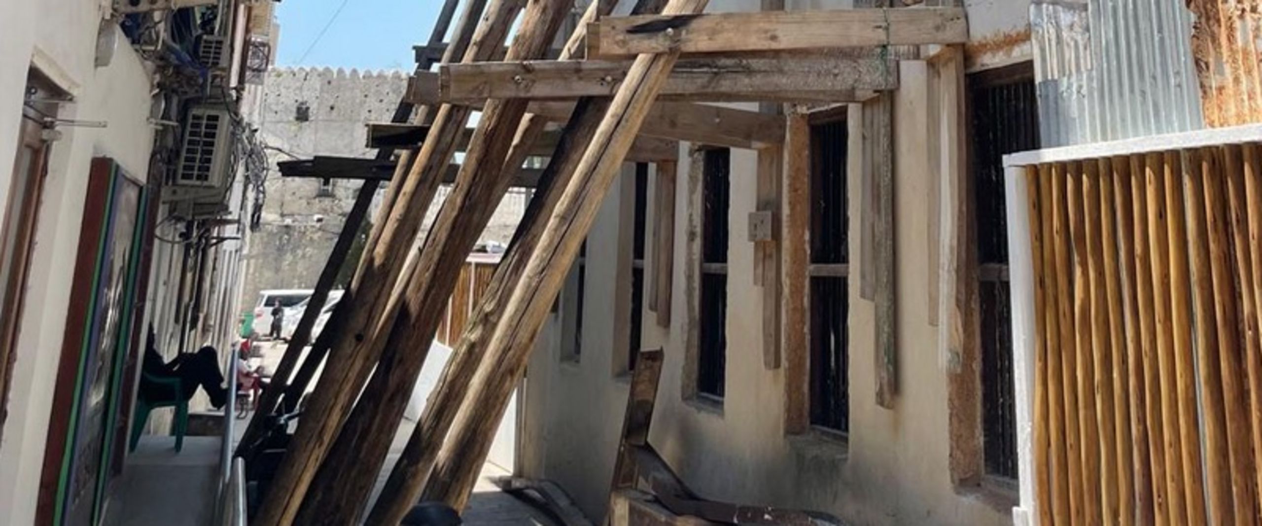 2026 Projekt Sassibar CO3 Bild zeigt schmale Gasse. Die Hausfassaden sind sanierungsbedürftig. Die rechte stützt ein Holzgerüst.