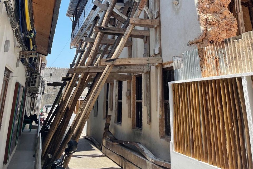 2026 Projekt Sassibar CO3 Bild zeigt schmale Gasse. Die Hausfassaden sind sanierungsbedürftig. Die rechte stützt ein Holzgerüst.