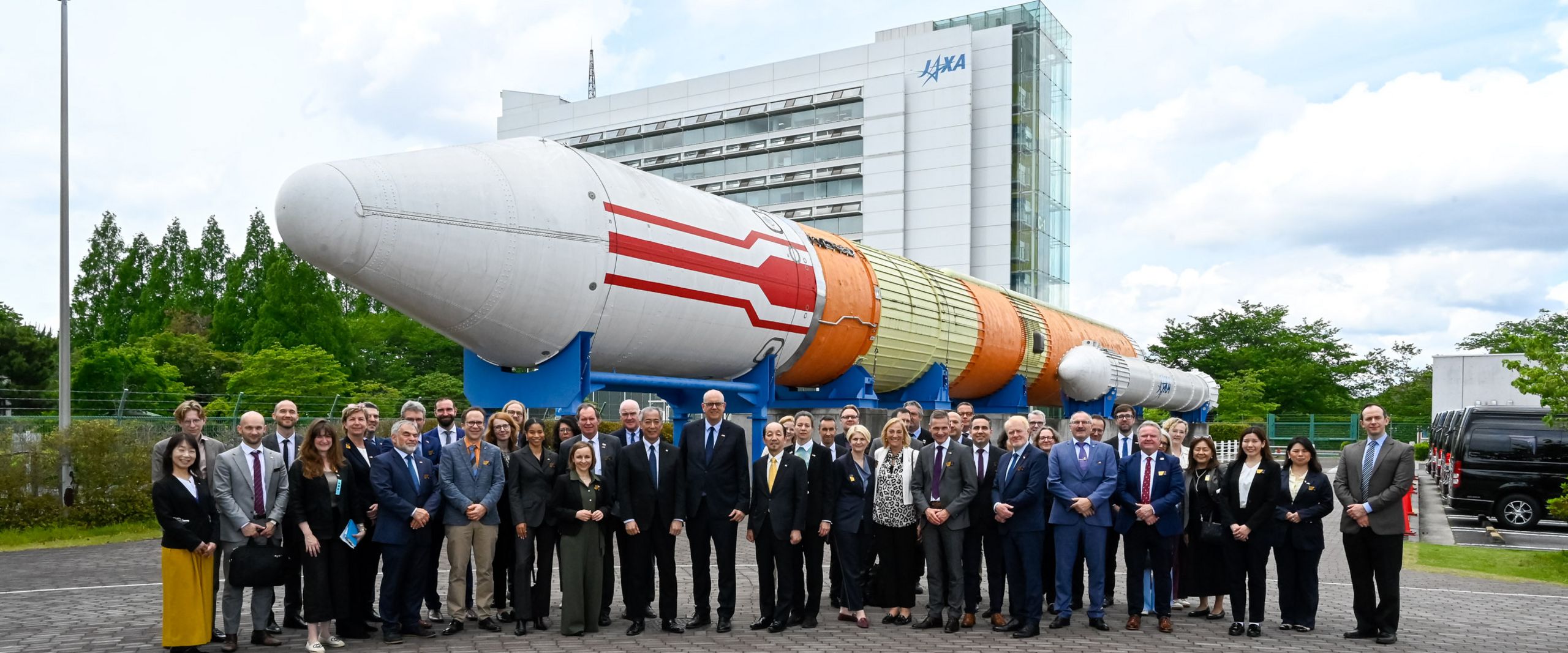 Gruppenbild mit M&auml;nnern und Frauen. Im Hintergrund ist eine Rakete als Exponat zu sehen