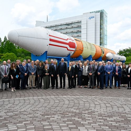 Gruppenbild mit M&auml;nnern und Frauen. Im Hintergrund ist eine Rakete als Exponat zu sehen