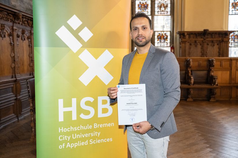 Mann mit Urkunde vor einem Banner