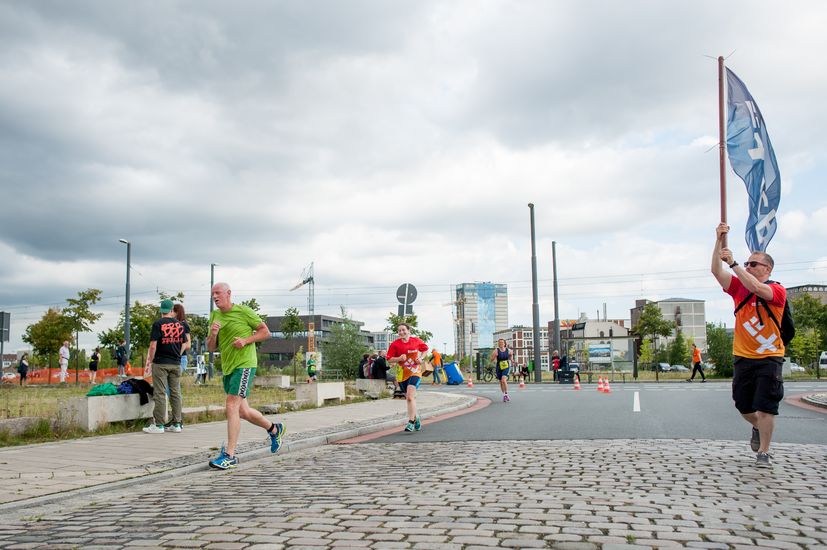 L&auml;ufer rennen auf der Strecke und an der Seite stehen Zuschauer.