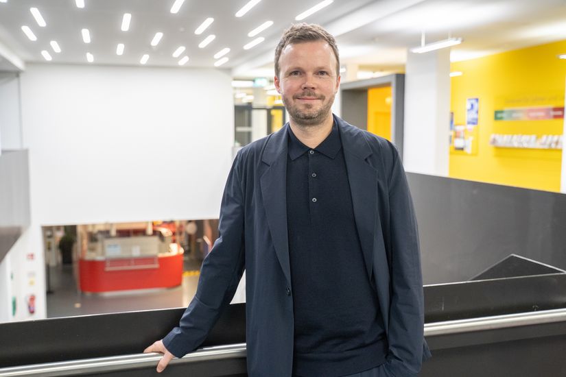 Mann mit Bart lehnt an Gel&auml;nder und schaut in die Kamera