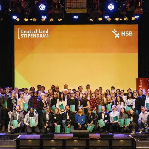 Gruppenbild mit lachenden M&auml;nnern und Frauen auf einer B&uuml;hne