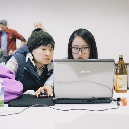 Zwei Studierende im Vorlesungsraum vor einem Laptop.