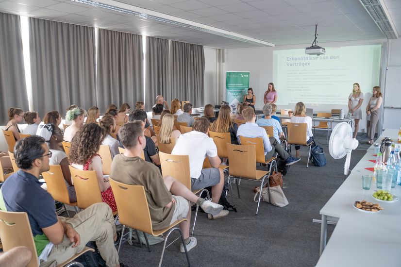 Raum mit besetzten Stühlen auf den Studierende der Learners Company 2025 sitzen. Ein Präsentation läuft im Hintergrund.