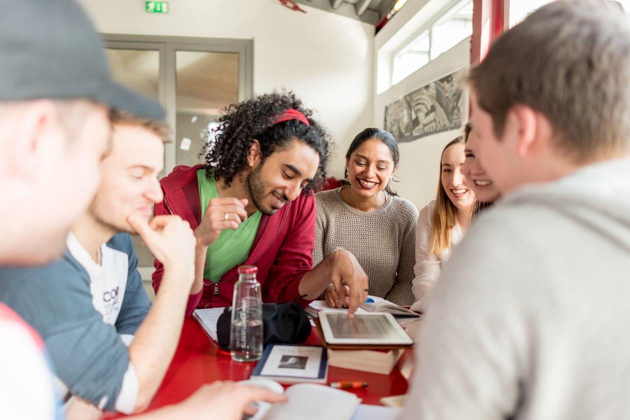 Jungen Menschen sitzen am Tisch und sind im Gespräch